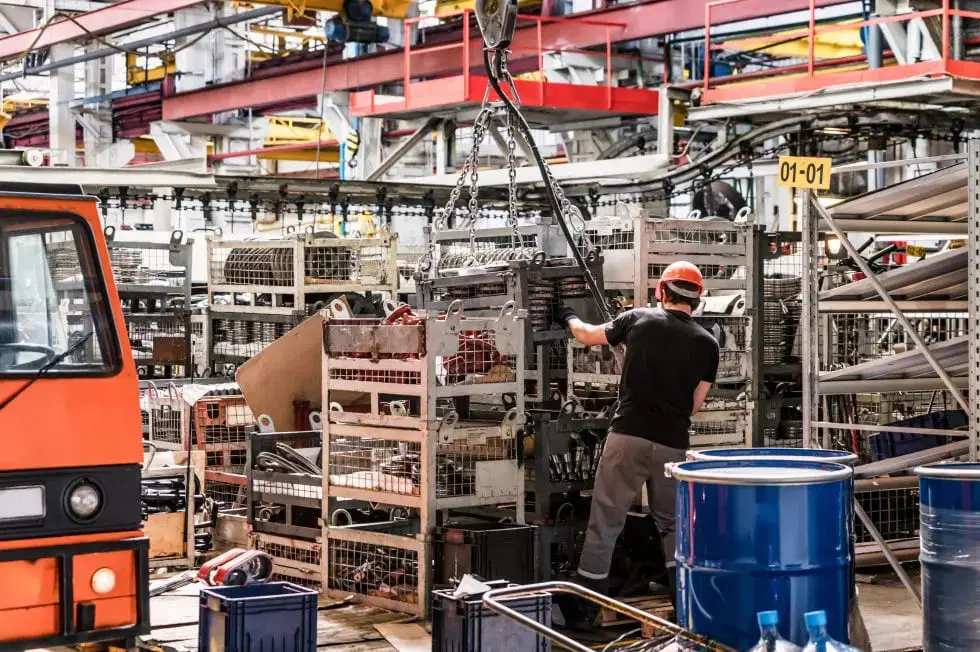 Close-up image of man at assembly room at big industrial plant manufacturing tractors and harvesters