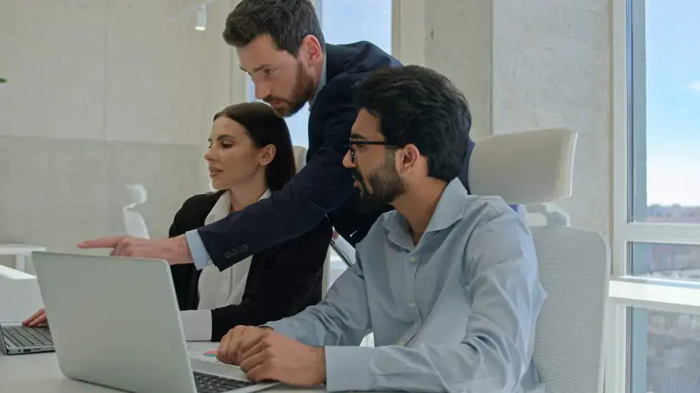 Diverse team corporate coworkers working laptops in office male business coach mentor boss businessman helping employees with computer work training new workers help interns check explain data project. High quality 4k footage
